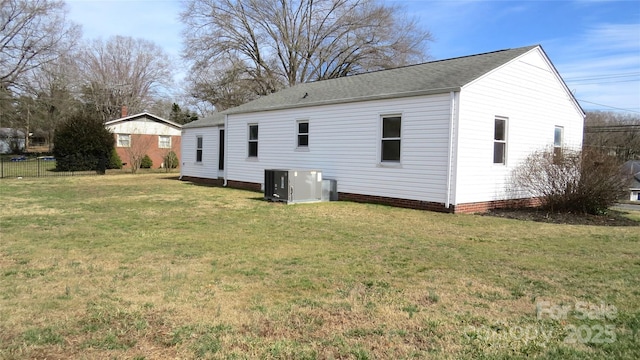 back of house with central AC unit and a lawn