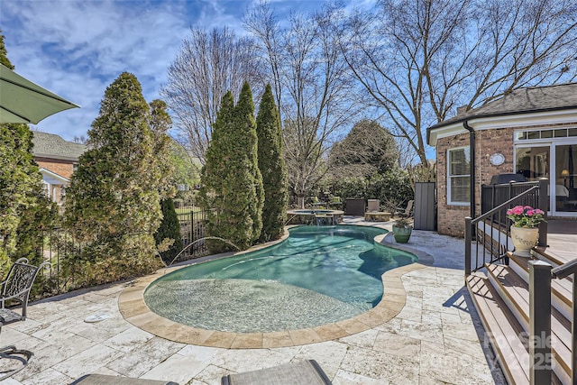 view of swimming pool with a patio, fence, and a pool with connected hot tub