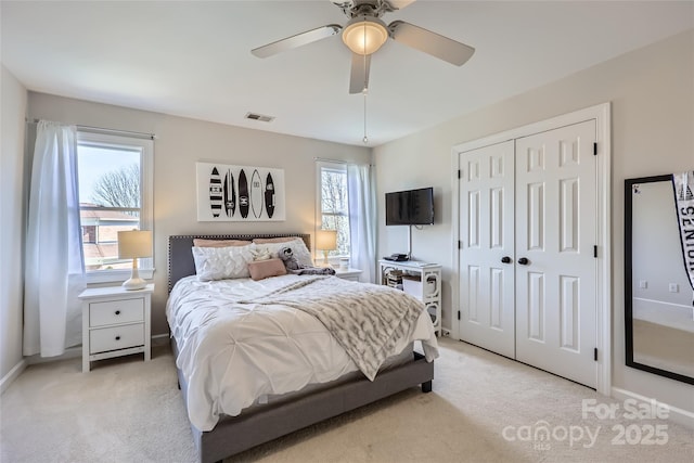 bedroom with a ceiling fan, a closet, visible vents, and light carpet