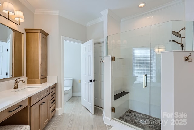 bathroom with a stall shower, crown molding, vanity, and toilet