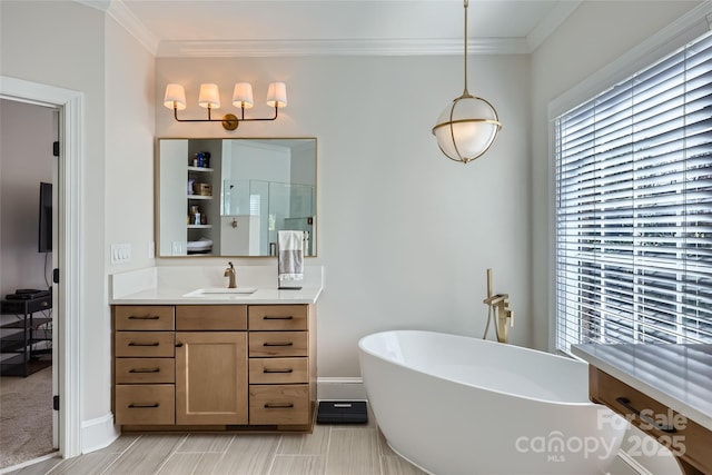 bathroom featuring baseboards, a freestanding tub, vanity, and crown molding