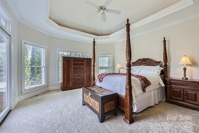 bedroom featuring light carpet, a tray ceiling, multiple windows, and ornamental molding