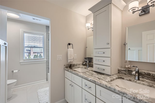 full bath featuring double vanity, baseboards, toilet, and a sink