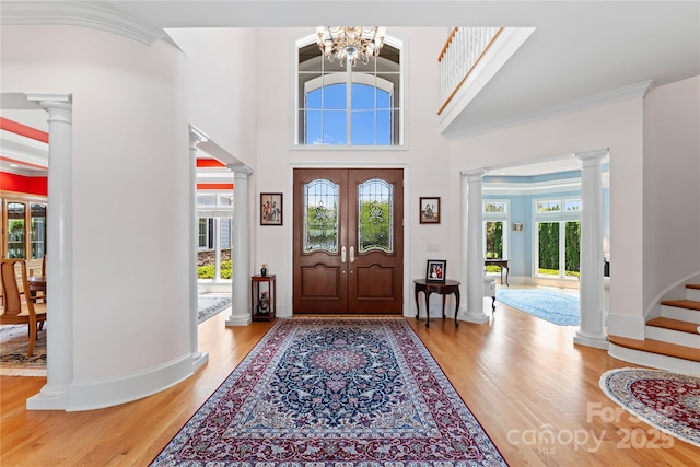 entrance foyer featuring plenty of natural light, light wood-type flooring, and decorative columns