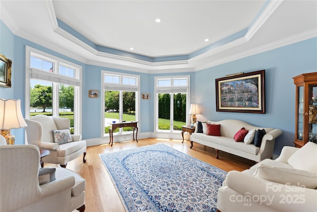 living area with crown molding, baseboards, recessed lighting, wood finished floors, and a raised ceiling