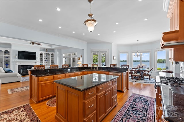 kitchen with a large island, light wood-style flooring, a sink, open floor plan, and brown cabinetry