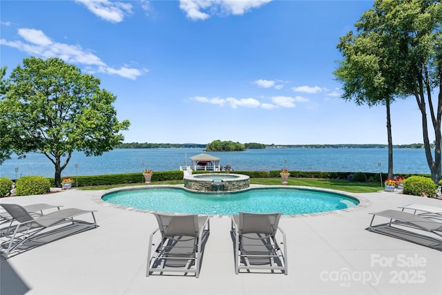 view of pool featuring a pool with connected hot tub, a patio, and a water view