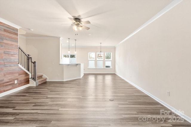 unfurnished living room featuring ornamental molding, wood finished floors, and stairs