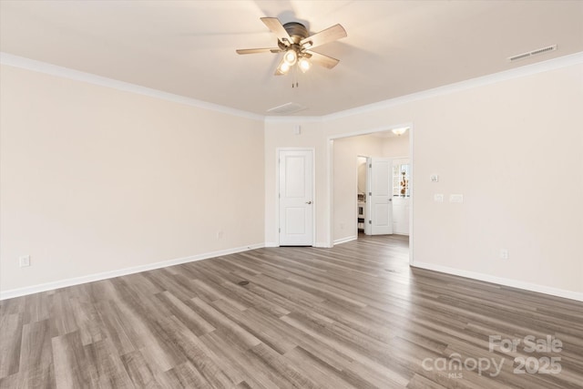 spare room with crown molding, visible vents, ceiling fan, wood finished floors, and baseboards