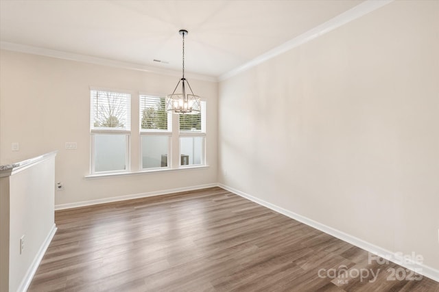 unfurnished dining area featuring a chandelier, ornamental molding, baseboards, and wood finished floors