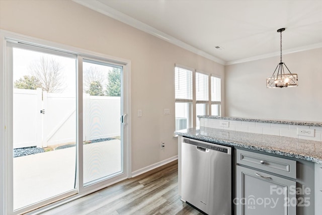 kitchen featuring decorative light fixtures, crown molding, wood finished floors, stainless steel dishwasher, and light stone countertops