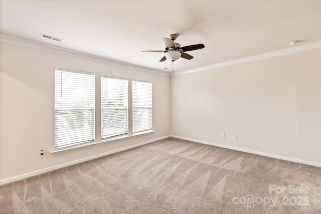 spare room with baseboards, carpet, visible vents, and crown molding