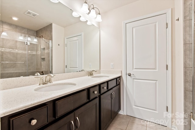 bathroom with double vanity, a stall shower, a sink, and tile patterned floors