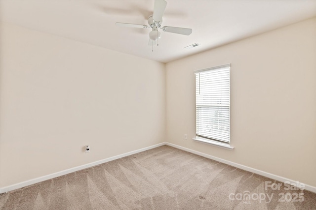 empty room with a ceiling fan, light colored carpet, visible vents, and baseboards