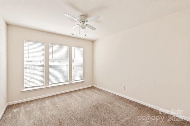 carpeted empty room with visible vents, ceiling fan, and baseboards