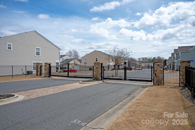 view of road featuring curbs, a gated entry, a residential view, and a gate