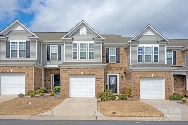 townhome / multi-family property with concrete driveway, brick siding, and an attached garage