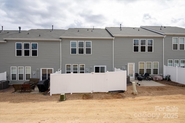 rear view of house with central air condition unit, a patio, and fence