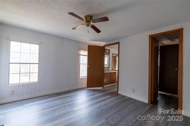 unfurnished room featuring a ceiling fan, plenty of natural light, a textured ceiling, and wood finished floors