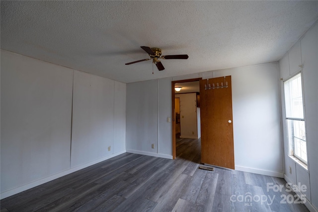 unfurnished room with a textured ceiling, ceiling fan, dark wood finished floors, and visible vents