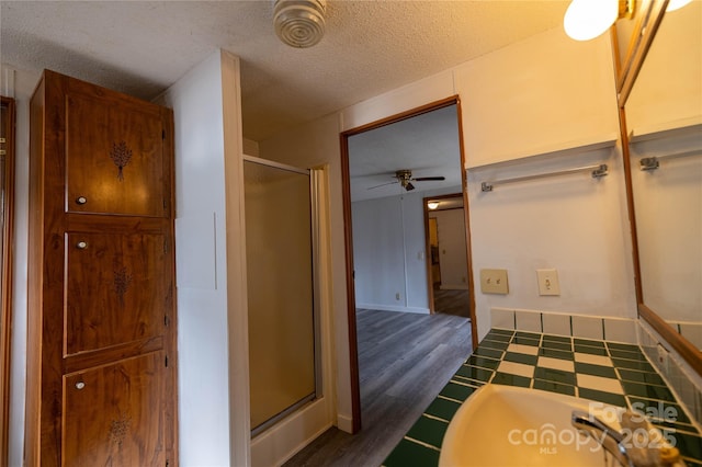 bathroom featuring a shower stall, a ceiling fan, and a textured ceiling