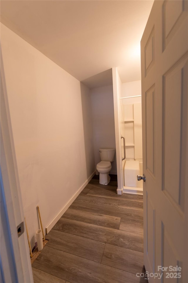 bathroom featuring toilet, shower / tub combination, baseboards, and wood finished floors