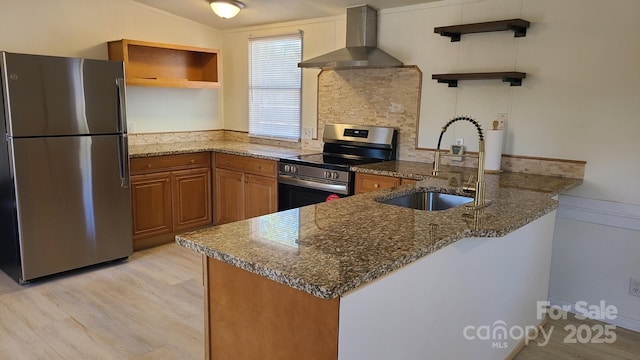 kitchen featuring open shelves, appliances with stainless steel finishes, a sink, wall chimney range hood, and a peninsula