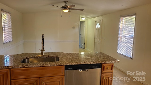 kitchen with a sink, dark stone counters, brown cabinetry, and dishwasher