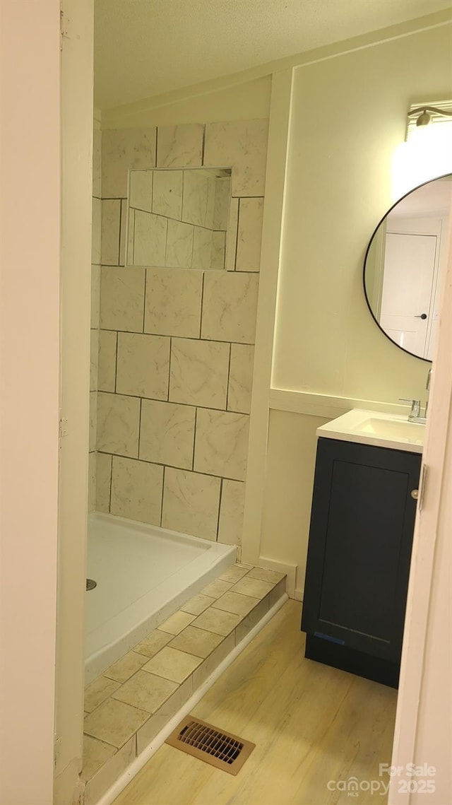 bathroom with visible vents, wood finished floors, a shower stall, and vanity