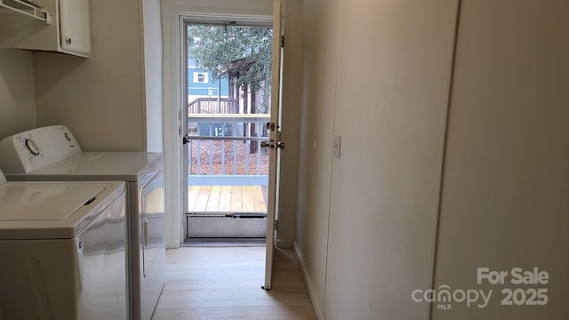 laundry area with light wood-style flooring, plenty of natural light, washing machine and clothes dryer, and cabinet space