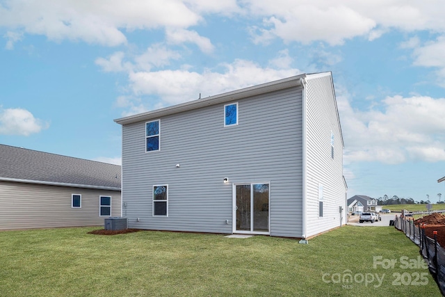 back of house featuring a lawn, fence, and central AC unit