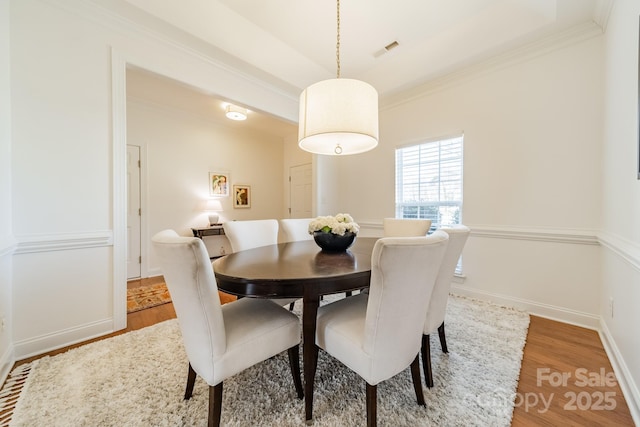 dining space with ornamental molding, visible vents, baseboards, and wood finished floors