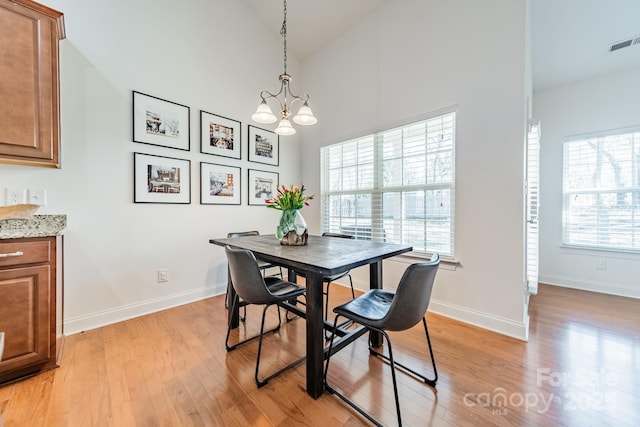 dining space with high vaulted ceiling, visible vents, a chandelier, light wood-type flooring, and baseboards