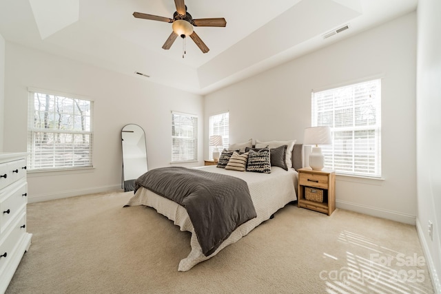 bedroom with light carpet, a tray ceiling, visible vents, and baseboards