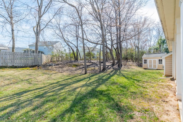 view of yard with an outbuilding, a storage unit, and fence