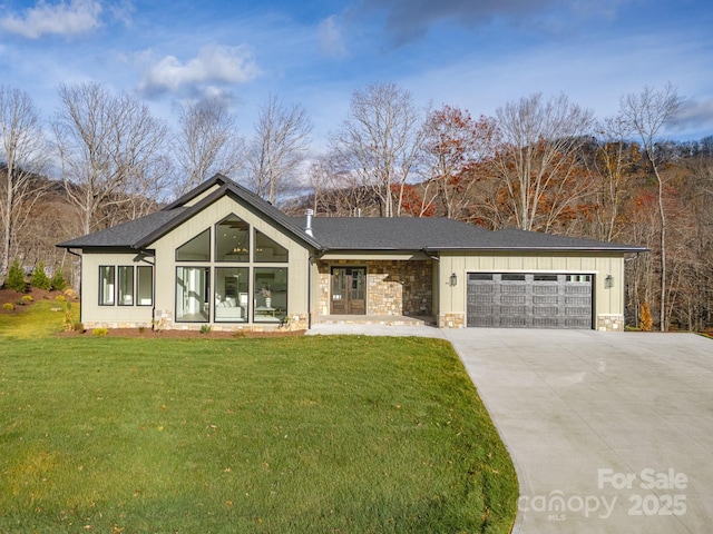 view of front of house with an attached garage, stone siding, concrete driveway, a front lawn, and board and batten siding