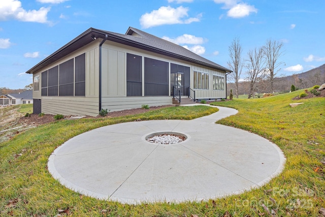 rear view of property featuring a sunroom, board and batten siding, and a yard