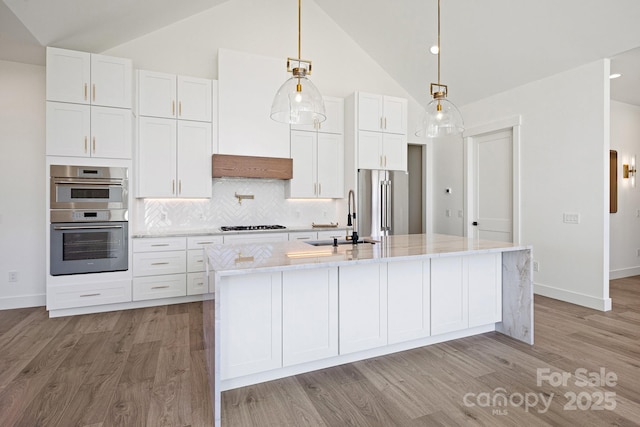 kitchen with appliances with stainless steel finishes, white cabinets, a sink, and tasteful backsplash