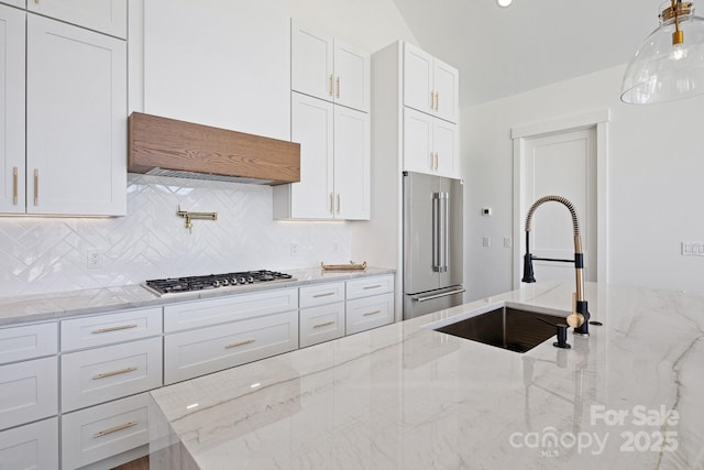 kitchen featuring a sink, white cabinetry, high end fridge, backsplash, and stainless steel gas stovetop