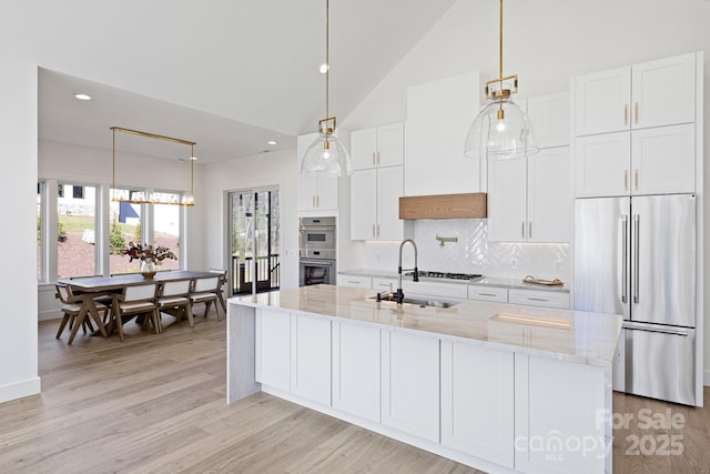 kitchen featuring stainless steel appliances, white cabinets, backsplash, and light wood finished floors