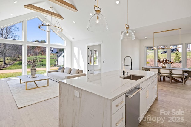 kitchen with white cabinets, a sink, light stone countertops, high vaulted ceiling, and light wood-type flooring