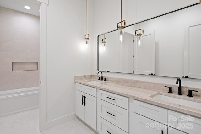 bathroom featuring marble finish floor, a sink, baseboards, and double vanity