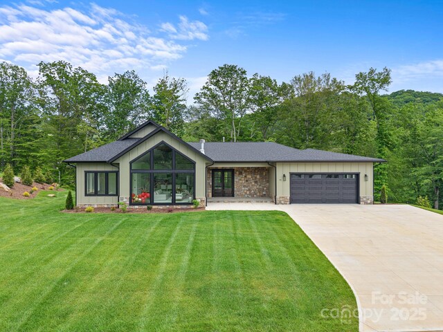 90 Bridgeway Dr Unit 25, Candler, NC 28715 - mid-century modern home featuring a garage, a front lawn, concrete driveway, a shingled roof, and board and batten siding