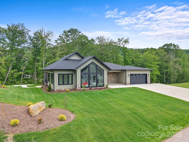 90 Bridgeway Dr Unit 25, Candler, NC 28715 - view of front facade with driveway, a front yard, an attached garage, a wooded view, and board and batten siding