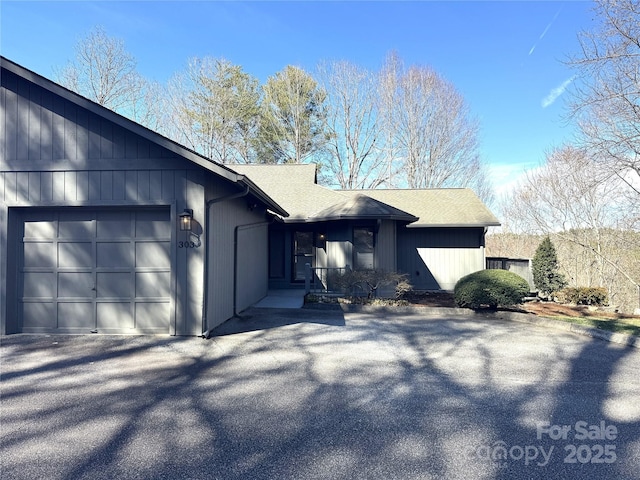 view of front of property with a garage, roof with shingles, and aphalt driveway