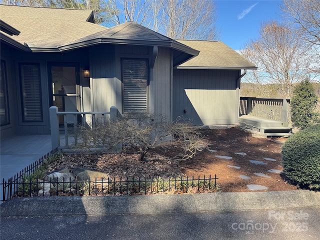 view of home's exterior featuring a shingled roof and fence