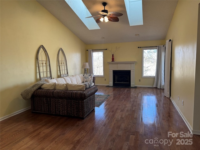 living room with vaulted ceiling with skylight, dark wood finished floors, a fireplace with flush hearth, and a wealth of natural light