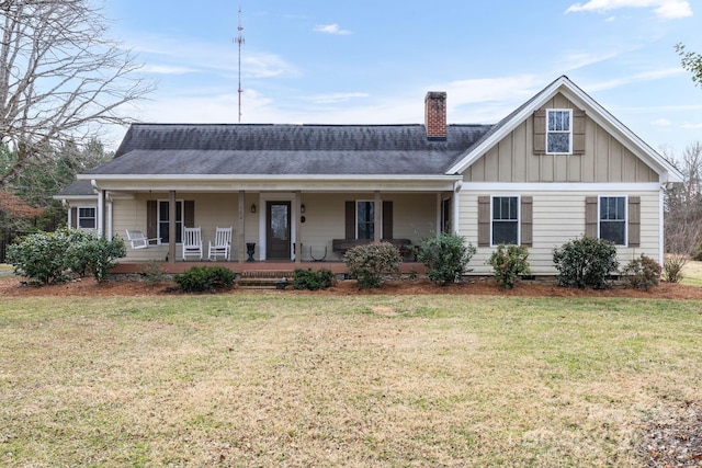 view of front facade featuring covered porch, a front yard, crawl space, board and batten siding, and a chimney