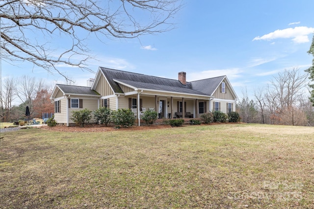 view of front of property with covered porch, a front lawn, board and batten siding, and a chimney