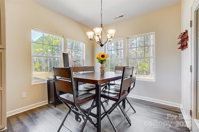 dining space featuring a chandelier, wood finished floors, visible vents, and baseboards